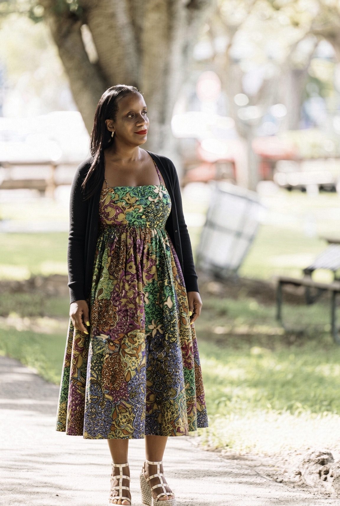 Charisa D. Strong standing outdoors in a park, wearing a green and purple print dress